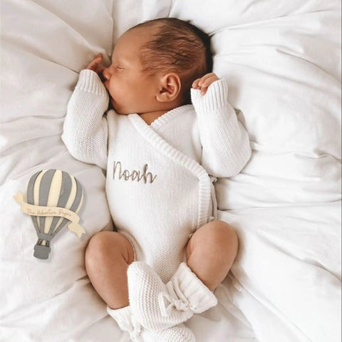 Newborn in white outfit with Wooden Hot Air Balloon Monthly Milestone Cards For Babies, My First Year Sign beside him.