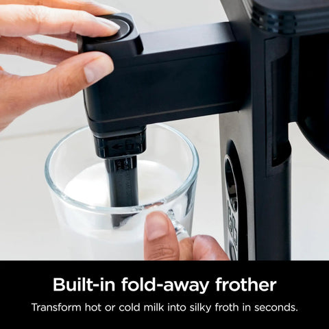 Specialty Coffee Maker For Hot And Iced Brews With Four Styles Classic Rich Over Ice And Specialty Brew Eight Size Options From Small Cup To Travel Mug Ten Cup Carafe Fold Away Frother Permanent Filter Removable Reservoir Black in use, showing fold-away frother in a glass of milk.