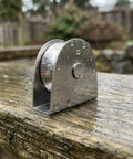 Heavy Duty V Groove Pulley Wheel 304 Stainless Steel Flagpole Riser Kit on a wet wooden surface, showcasing its smooth operation.