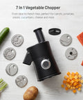 7-in-1 Electric Vegetable Chopper And Mincer With 7 Stainless Steel Blades For Fast Slicing Dicing And Shredding Of Potatoes Onions Carrots And Cheese on a countertop with fresh veggies.