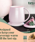 Self Heating Mug With Phone Controlled Heat Settings And Wireless Charging Stand To Keep Your Morning Brew Piping Hot All Day Long Sip At Your Pace While This Rechargeable Tech Build Keeps Every Drop Cozy And Fresh in soft pink color with tea bag.