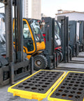 Yellow Spill Containment Platform With Grating, Stackable Modular System With Drain Outlet, Heavy Duty 20 Gallon Capacity in an industrial setting