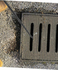 Rock Solid T Shaped Manhole Cover Lifter Hook Forged From Reinforced Steel Rod With A No Slip Grip reaching into a storm drain.