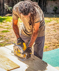 Person wearing General Utility Work Gloves GUG All Purpose Performance Fit Durable Machine Washable Small Black With Thermoplastic Rubber Knuckle Protection And Secure Hook And Loop Closure For A Snug Custom Fit On Tough Jobs using a circular saw outdoors.