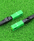 Two SC APC fiber optic quick connectors in green and black plastic for CATV networks, top-down view