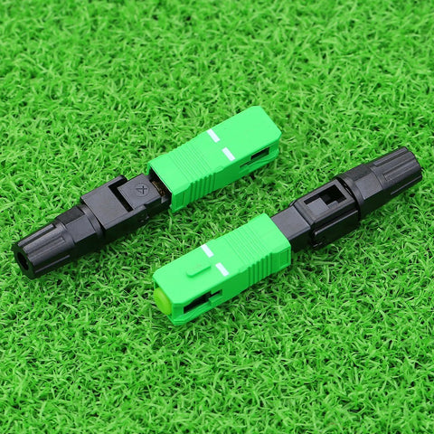 Two SC APC fiber optic quick connectors in green and black plastic for CATV networks, top-down view