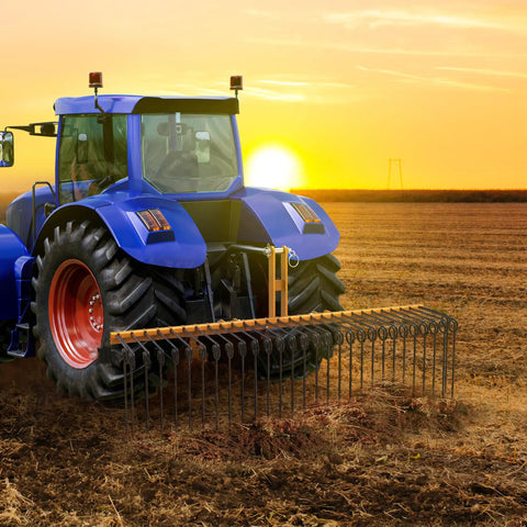 72 Inch Tow Behind Landscape Rake With 32 Steel Tine Dethatcher For Category 1 Tractors attached to a blue tractor at sunset
