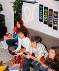 Friends gaming in a playroom with Glow In The Dark Gamer Wall Decals Four Piece Set Featuring Joystick Controller Stickers in blue.
