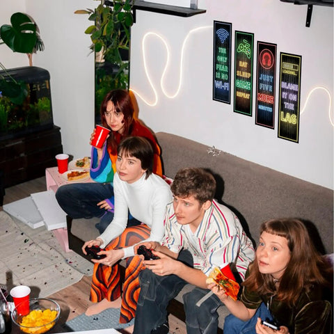 Friends gaming in a playroom with Glow In The Dark Gamer Wall Decals Four Piece Set Featuring Joystick Controller Stickers in blue.