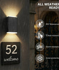 Hella Bright Solar Wall Light Outdoor Featuring Slick Up And Down Lighting above a welcome sign on a rainy wall.