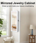 Wall-mounted full-length mirror jewelry cabinet with LED interior lights in a white room, featuring modern decor
