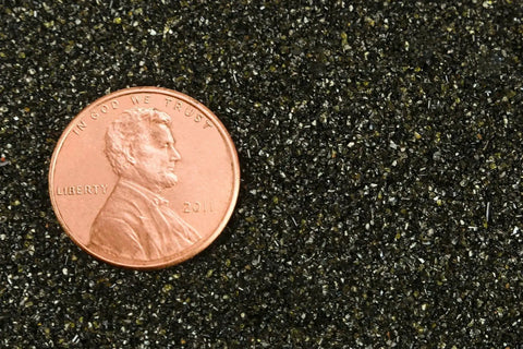Close-up of Extra Fine 30/60 Mesh Abrasive Blast Media for Sandblast Cabinets, with a penny for size comparison, shows texture and granularity.