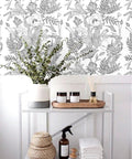 Peel And Stick Black White Lotus Lily Damask Wallpaper Mural For Easy DIY Decor on living room accent wall behind shelf setup.