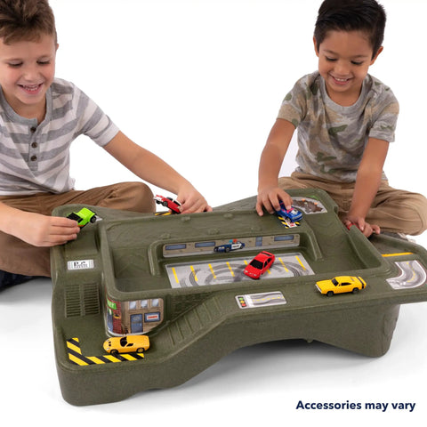 Two children playing with the Monster City Extreme Wheels Race Track Table For Kids, featuring cityscape and off-road tracks.