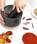 Hands using Durable Granite Mortar And Pestle Set With Wood Base For Grindin Herbs And Spices, Perfect For Guac And Salsa, Pepper And Nuts