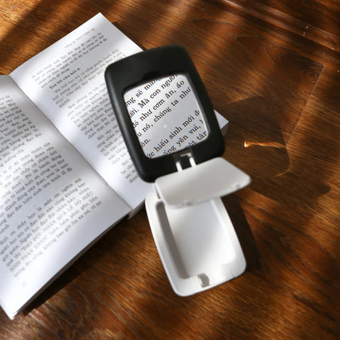 Pocket Magnifier With Light And Stand 3X Magnification Handy Portable 2-In-1 LED Desk Magnifier in use for reading text on a book