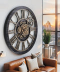 36 Inch Oversized Wall Clock With Real Moving Gears Vintage Industrial Decor Rustic Farmhouse Accent Piece Black Wood Bronze Finish mounted on wall above a modern sofa