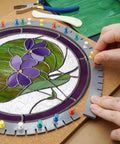Hand placing push pins on flexible silicone layout blocks around stained glass panel for crafting. 12 pack heat resistant mats.