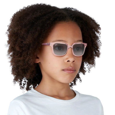 Child wearing RJ9071S Kids Square Sunglasses for Narrow Faces, Transparent Pink Frame With Light Gray Gradient Lenses, 48 mm