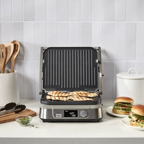 Cuisinart Griddler FIVE Electric Grill With Panini Press grilling chicken breasts on nonstick plates, LCD timer, and stainless steel base.