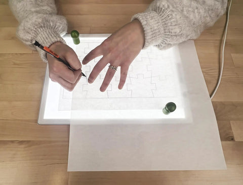 Person using Portable LED Light Pad For Crafting And Quilting 10 By 13 Inch, Ultra Bright Four Level Illumination For Clear Tracing And Cutting.