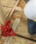 Guardian 2601 portable wall jack, red cast-iron clamp securing a wooden post on a construction site.