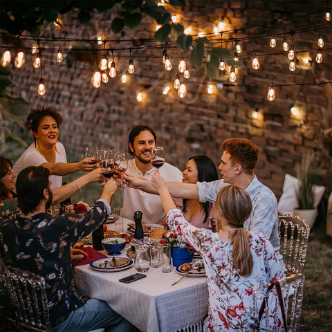 Outdoor dinner party under two 50 foot dimmable Edison style shatterproof string lights with 32 LED bulbs 100 feet total