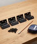 Heavy Duty Tri Fold Hinges For Cabinet Makeover, four black metal hinges with screws and measuring tape on wood surface.