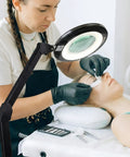 Esthetician using Hands Free Magnifying Floor Lamp With Dimmable LED Light, 5 Diopter Lens, Six Wheel Rolling Stand for lash extensions
