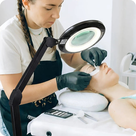 Esthetician using Hands Free Magnifying Floor Lamp With Dimmable LED Light, 5 Diopter Lens, Six Wheel Rolling Stand for lash extensions