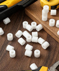 200 Pcs Heavy Duty Nylon Spacers White Half Inch Thick round insulated electrical outlet screw washers scattered on wood surface.