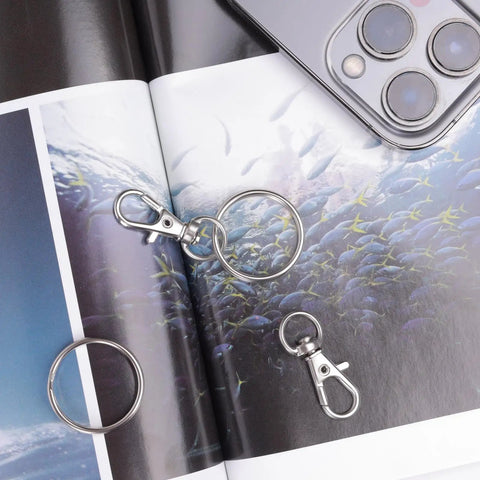 Hella Durable Premium Silver Swivel Snap Hooks 50 Pack Lobster Claw Trigger Clasps on photo album with fish design.