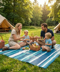Family picnic on Outdoor Patio Rug 4x6 Ft Waterproof Plastic Straw Style For Deck Garden Backyard, blue striped with food baskets.