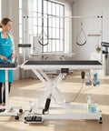 Heavy Duty Electric Dog Grooming Table With Smooth Operator Foot Pedal And Kickass Sturdy X Frame For Easy Height Adjustments And No Sweat Pet Styling In White with grooming tools and stylist.