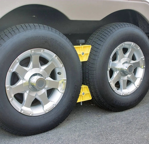 Side view of RV Wheel Stop for trailers in yellow, placed between tandem tires to stabilize and prevent shifting when parked.