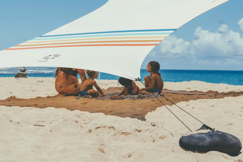 Family under Grande Portable Beach Tent Sun Shelter With 81 Sq Ft Shade 7 Ft Tall 9 By 9 Foot Canopy on beach