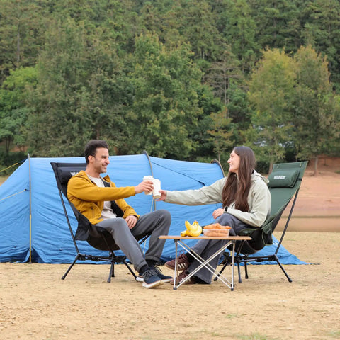 Couple enjoying drinks on Portable Lightweight Folding Camping Chair With High Back And Pillow, Deep Recline in campsite.
