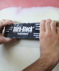 Hands using Six Piece Flexible EVA Foam Auto Body Sanding Block Kit for Wet or Dry Sanding on vehicle surface.
