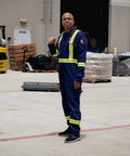 Man wearing Flame Resistant High Visibility Hi Vis Coverall In Royal Blue, 88 Percent Cotton And 12 Percent Nylon Twill, 7 Oz Workwear Built For Tough Jobs, Arc Flash Rated 12 Cal Per Cm2, NFPA 2112, HRC 2 Certified, Size Large, standing in an industrial setting.