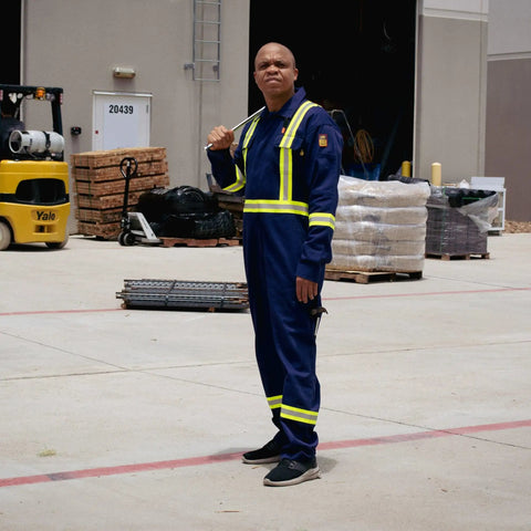 Man wearing Flame Resistant High Visibility Hi Vis Coverall In Royal Blue, 88 Percent Cotton And 12 Percent Nylon Twill, 7 Oz Workwear Built For Tough Jobs, Arc Flash Rated 12 Cal Per Cm2, NFPA 2112, HRC 2 Certified, Size Large, standing in an industrial setting.