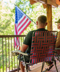Two people sitting on a porch in Retro Webbed Camping Chair With Foldable Steel Frame Lightweight 8 Lb Seat Heavy Duty 300 Lb Capacity Old School Red White And Blue Stripes Classic Outdoor Beach Camp Chair, looking at an American flag.