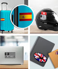Multiple items with various flag stickers, including Spain on suitcase and Union Jack on mouse, showcasing vinyl decals on surfaces.