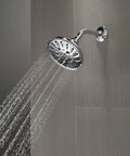 Mounted 5-Setting H2OKinetic Trad Raincan Shower Head in Matte Black spraying water, Easy Touch Clean spray holes visible.