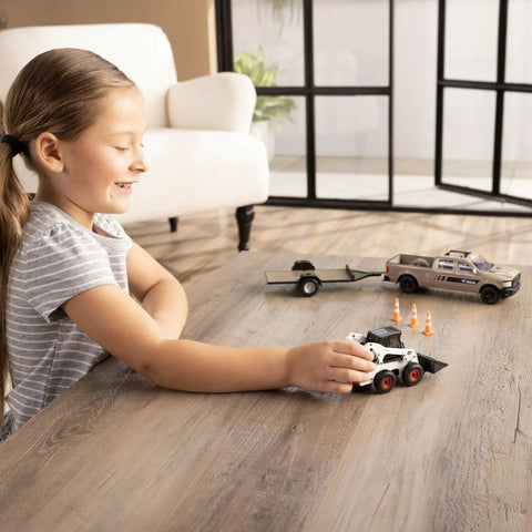 Child playing indoors with One Thirty Two Scale Die Cast Skid Steer And Pickup Truck Construction Toy Set With Trailer And Cones