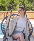 Person relaxing in Chill Out Hammock Chair With Macrame Swing by the poolside, handwoven cotton rope, grey