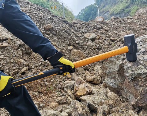 Person using 10 Pound Sledge Hammer for Heavy Duty Demolition with 35 Inch Fiberglass Handle on rocky terrain