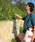 Man using Lightweight 1.3 Gallon Lawn And Garden Sprayer With Pressure Relief Valve, Adjustable Shoulder Strap, Adjustable Wand Nozzle in garden
