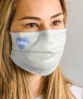 Person wearing light-colored face mask with blue heart logo.