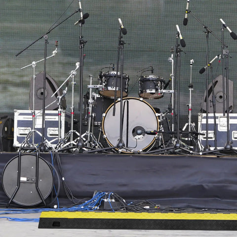 Stage setup with audio equipment and a Beefed Up Heavy Duty 5 Pack TPU Cable Protector Ramp with 2 channel design in foreground