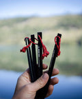 Hand holding Beefy 16 Pack 7075 Aluminum Tent Stakes 7.25 Inch Long Heavy Duty Ground Pegs Rust Resistant For Camping Canopy And Tarp